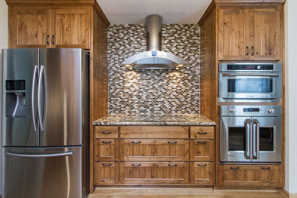 Large mountain style light wood floor eat-in kitchen photo with a farmhouse sink, light wood cabinets, granite countertops, beige backsplash, glass tile backsplash, stainless steel appliances and beige countertops
