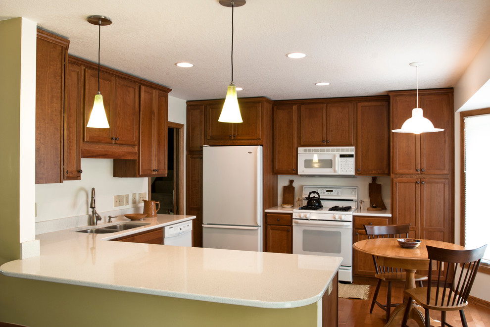 Inspiration for a mid-sized traditional u-shaped eat-in kitchen in Minneapolis with an undermount sink, flat-panel cabinets, medium wood cabinets, granite benchtops, white appliances, medium hardwood floors and no island.