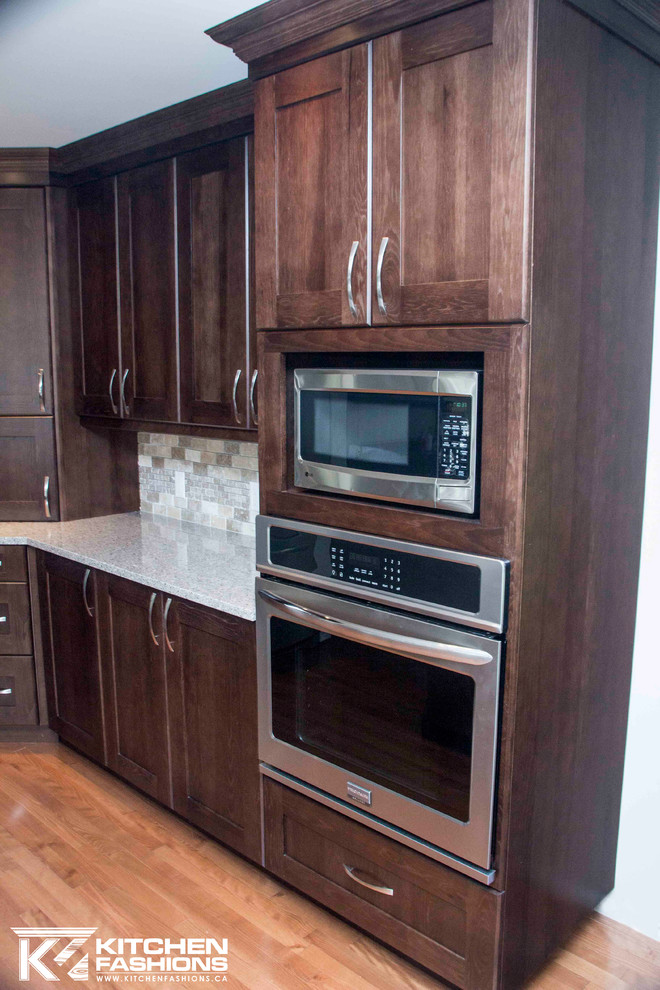 Open concept kitchen - large transitional u-shaped medium tone wood floor open concept kitchen idea with a farmhouse sink, shaker cabinets, dark wood cabinets, quartz countertops, brown backsplash, stone tile backsplash, stainless steel appliances and an island