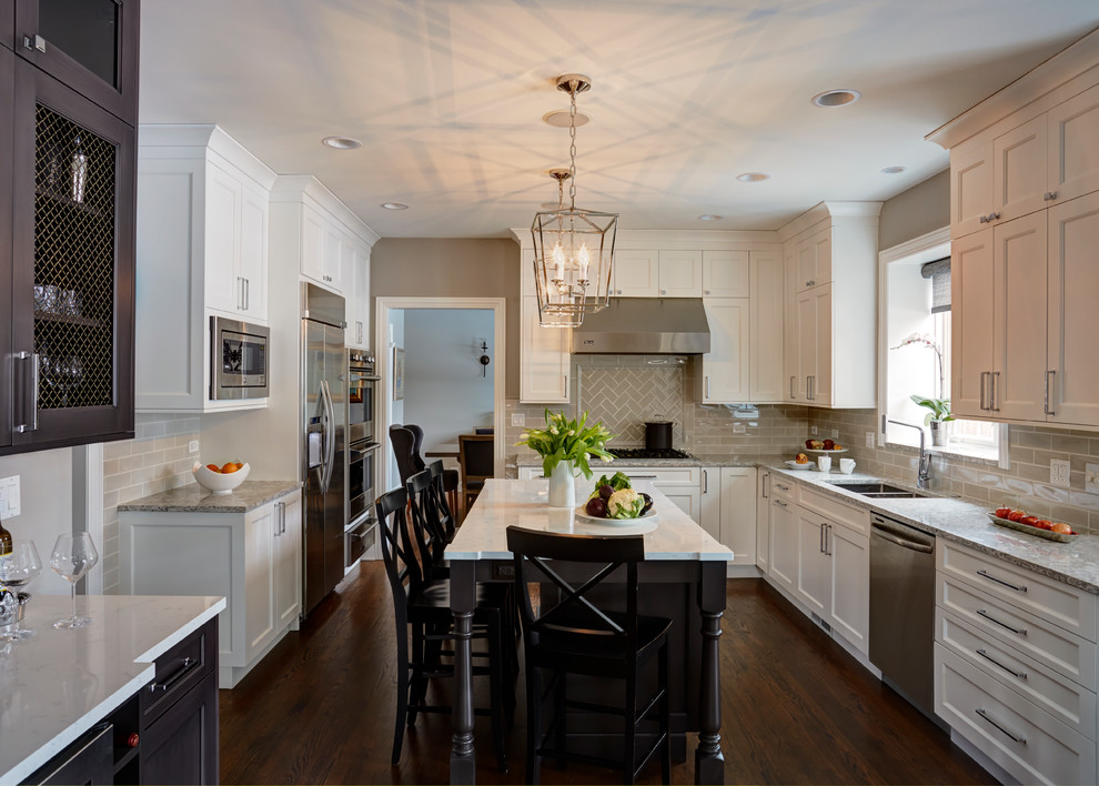 This is an example of a large transitional u-shaped open plan kitchen in Chicago with a double-bowl sink, flat-panel cabinets, white cabinets, quartz benchtops, beige splashback, subway tile splashback, stainless steel appliances, medium hardwood floors and with island.