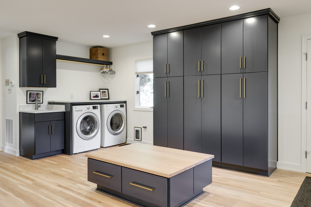 Inspiration for an expansive modern dedicated laundry room in Richmond with an integrated sink, flat-panel cabinets, blue cabinets, wood benchtops, white walls, light hardwood floors, a side-by-side washer and dryer and beige benchtop.