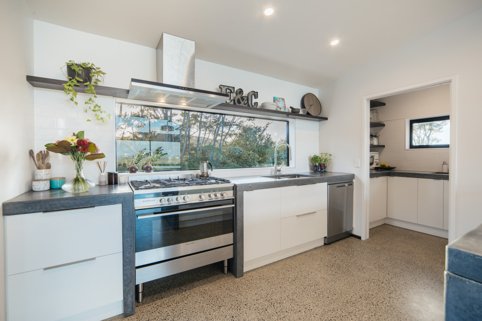 Inspiration for a Mid-sized modern Single-wall eat-in kitchen in Auckland With an Undermount Sink, Recessed-panel Cabinets, White Cabinets, Concrete Benchtops, White Splashback, Subway Tile Splashback, Stainless Steel Appliances, Concrete Floors, with Island, Grey Floor, Grey Benchtop and Vaulted.