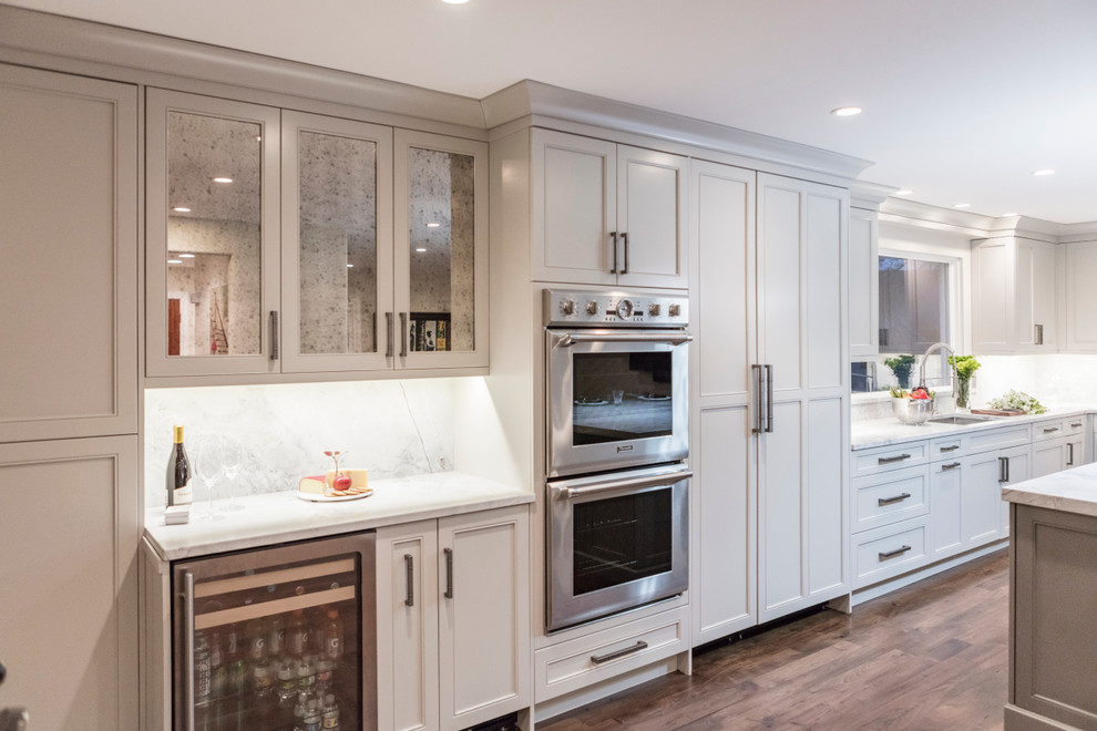 Inspiration for a large transitional l-shaped medium tone wood floor and brown floor open concept kitchen remodel in DC Metro with a double-bowl sink, beaded inset cabinets, gray cabinets, marble countertops, stainless steel appliances, an island, white backsplash and marble backsplash