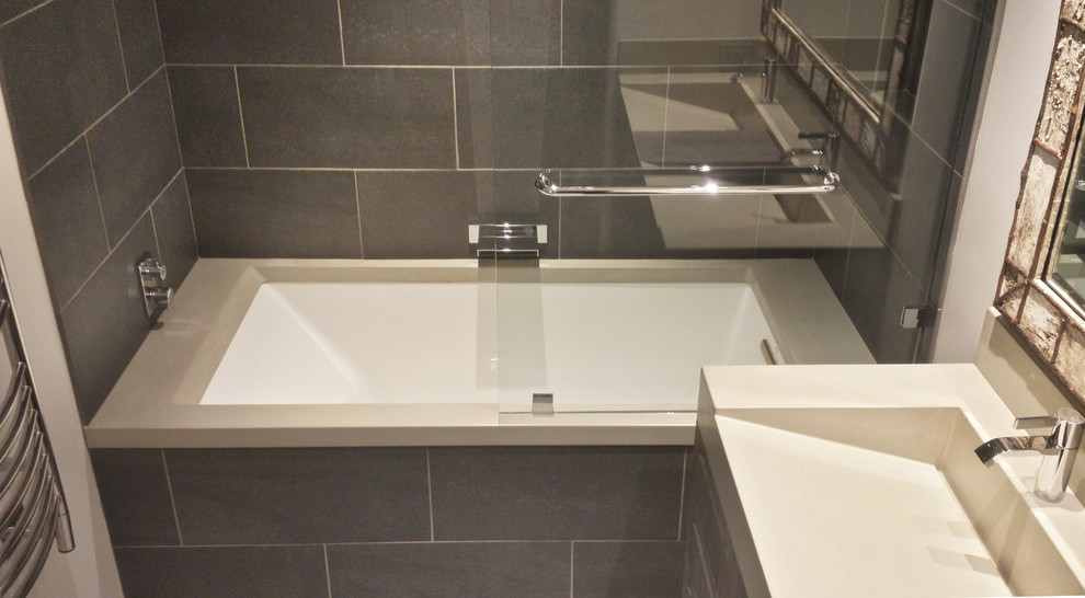 Bathroom - mid-sized transitional gray tile and ceramic tile bathroom idea with an integrated sink, flat-panel cabinets, dark wood cabinets, concrete countertops, an undermount tub and white walls