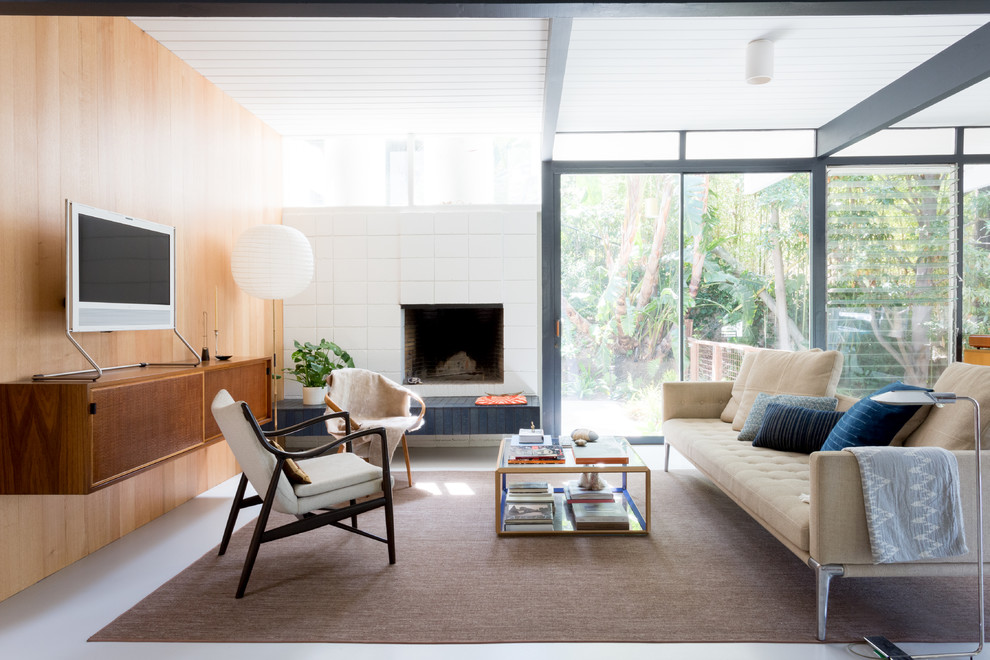 This is an example of a mid-sized midcentury formal living room in Los Angeles with multi-coloured walls, a standard fireplace, a freestanding tv and white floor.