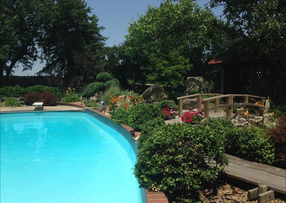 Photo of a large transitional partial sun backyard brick landscaping.
