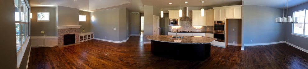 Example of a transitional l-shaped medium tone wood floor open concept kitchen design in Denver with an undermount sink, recessed-panel cabinets, dark wood cabinets, granite countertops, beige backsplash, stone tile backsplash, stainless steel appliances and an island