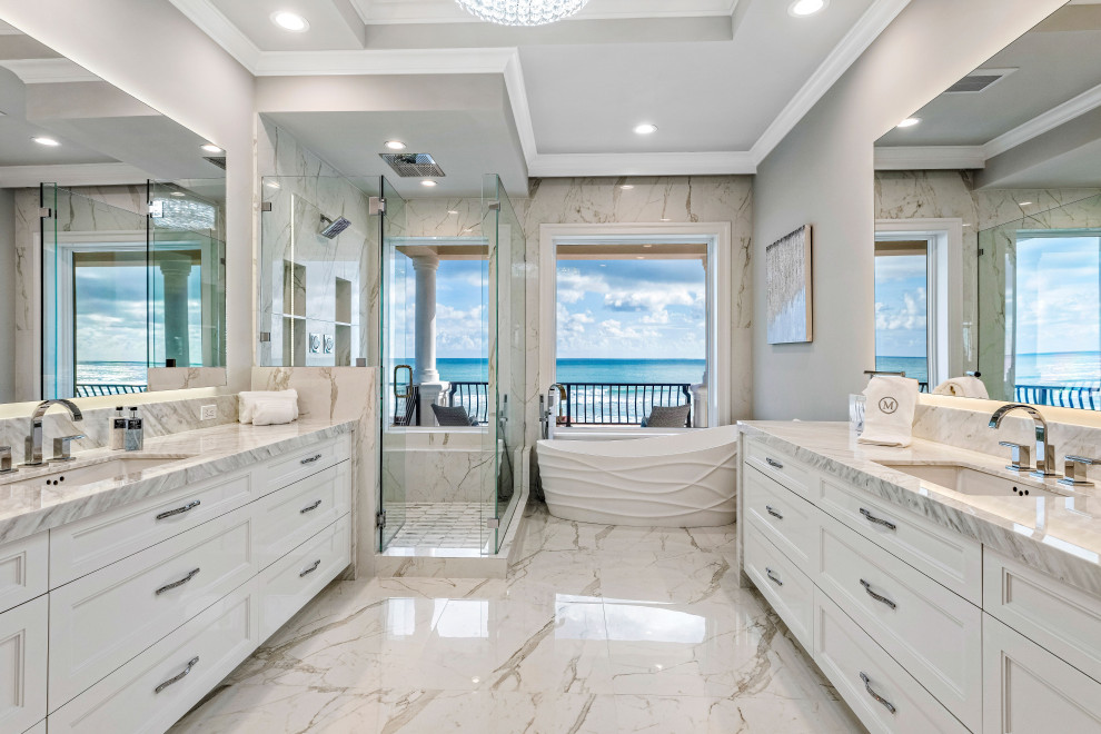 Idéer för att renovera ett stort funkis grå grått en-suite badrum, med luckor med infälld panel, vita skåp, ett fristående badkar, en öppen dusch, vit kakel, porslinskakel, vita väggar, klinkergolv i porslin, ett undermonterad handfat, marmorbänkskiva, vitt golv och dusch med gångjärnsdörr