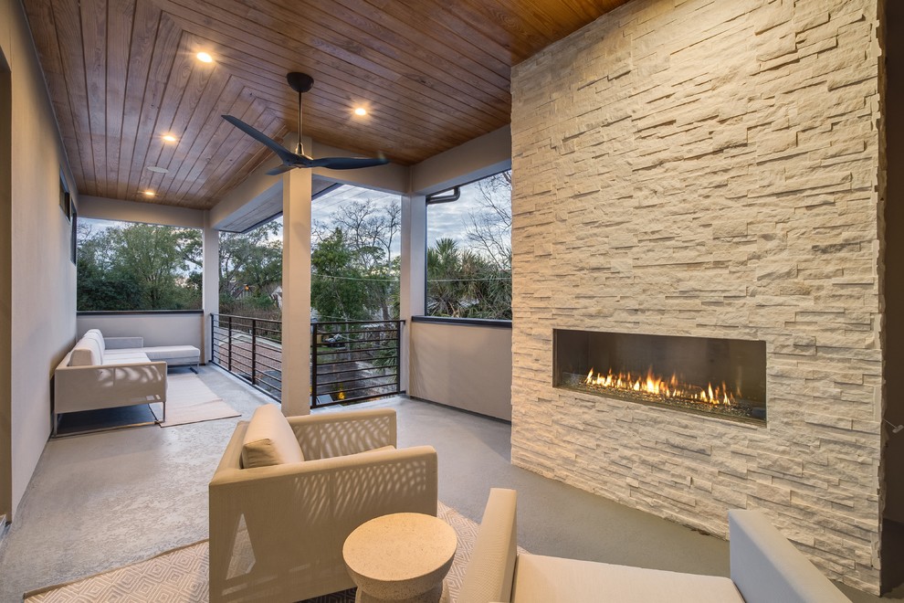 Photo of a mid-sized transitional balcony with with fireplace, a roof extension and metal railing.