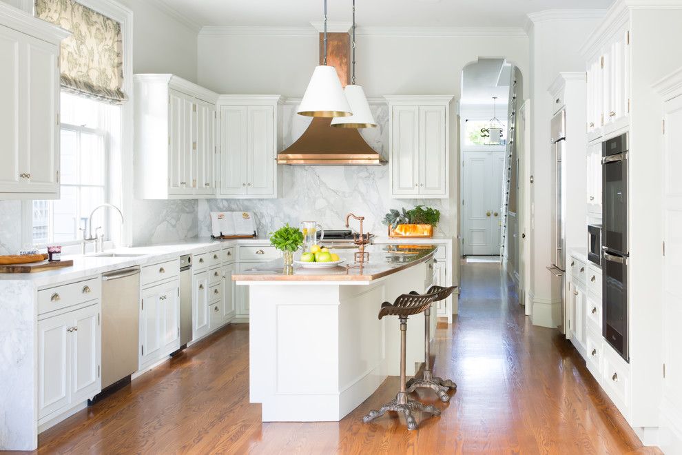 Design ideas for a transitional u-shaped kitchen in San Francisco with an undermount sink, recessed-panel cabinets, white cabinets, copper benchtops, white splashback, stone slab splashback, stainless steel appliances, medium hardwood floors, with island and brown floor.