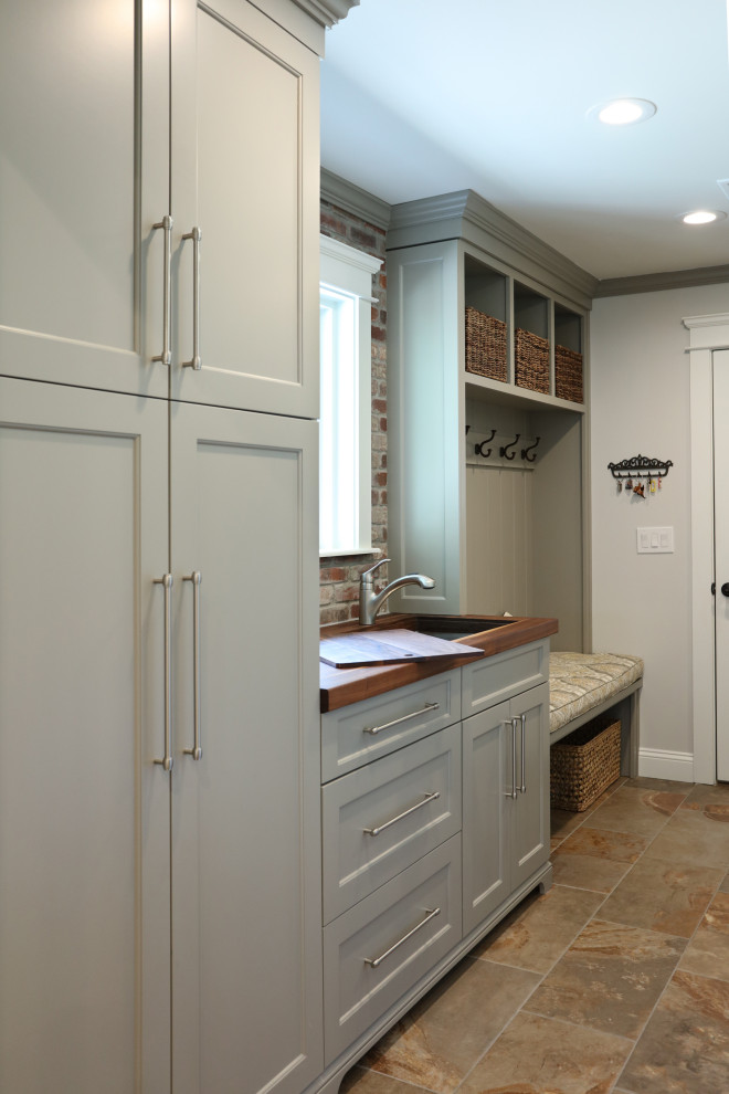 Mid-sized traditional galley utility room in Atlanta with an utility sink, recessed-panel cabinets, grey cabinets, wood benchtops, grey walls, porcelain floors, a side-by-side washer and dryer, brown floor and multi-coloured benchtop.