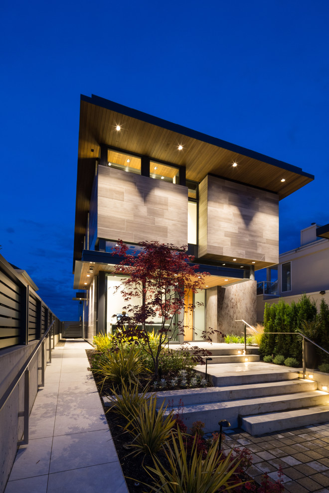 This is an example of a small contemporary two-storey grey exterior in Vancouver with stone veneer and a flat roof.