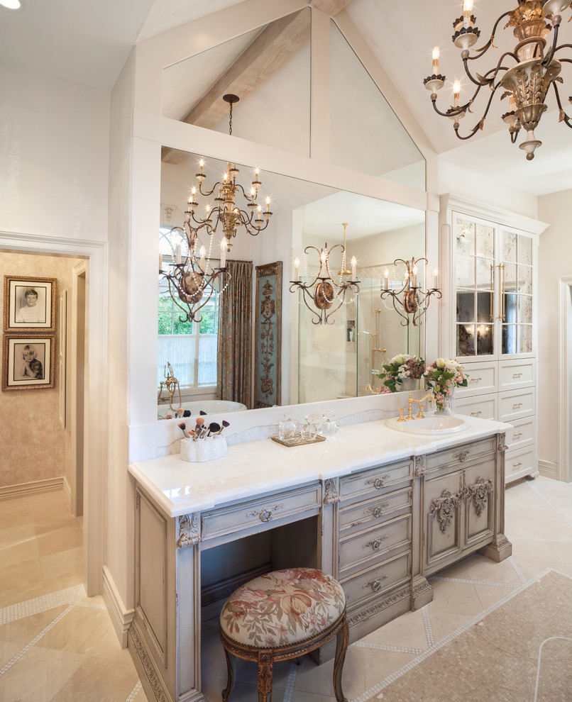 This is an example of a large traditional master bathroom in Other with a drop-in sink, furniture-like cabinets, beige cabinets, a freestanding tub, a corner shower, beige tile, stone tile, marble benchtops, white walls, marble floors, a single vanity and exposed beam.