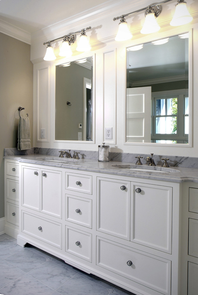 Design ideas for a large traditional master bathroom in Grand Rapids with marble benchtops, recessed-panel cabinets, white cabinets, beige walls, marble floors and an undermount sink.