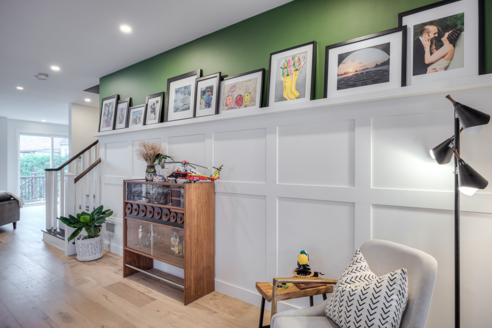 Cette image montre une petite salle à manger ouverte sur la cuisine nordique avec un mur vert, parquet clair, une cheminée standard, un manteau de cheminée en bois, un sol beige et boiseries.