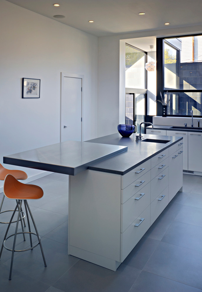 Mid-sized minimalist l-shaped porcelain tile eat-in kitchen photo in Chicago with an undermount sink, flat-panel cabinets, white cabinets, soapstone countertops, white backsplash and an island