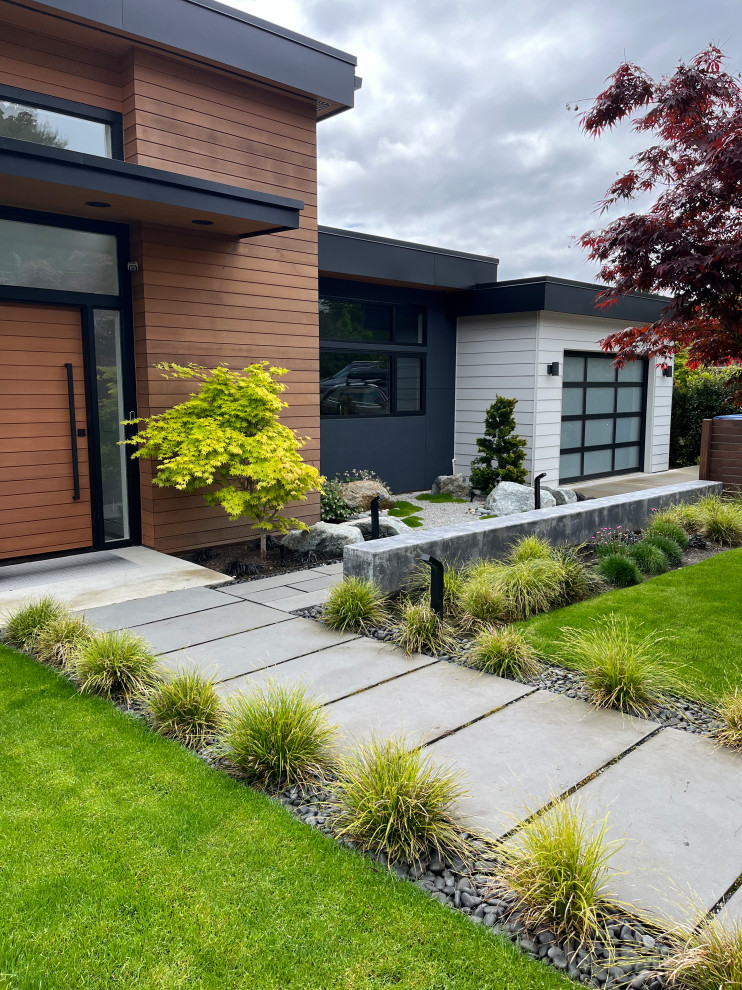 Esempio di un giardino moderno esposto in pieno sole di medie dimensioni e davanti casa con sassi e rocce e pavimentazioni in cemento