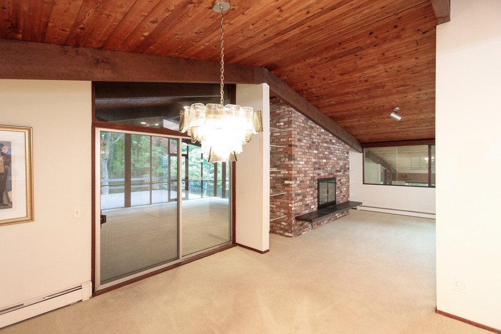 This is an example of a large midcentury enclosed family room in Boston with white walls, carpet, a standard fireplace, a brick fireplace surround and beige floor.