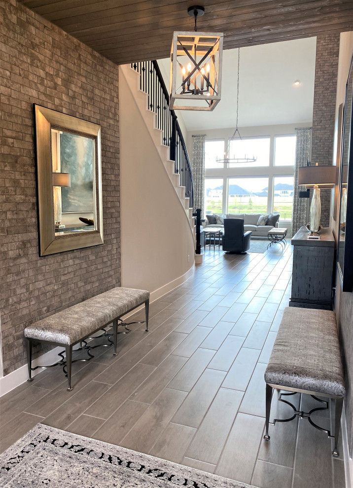 This is an example of a large transitional foyer in Houston with grey walls, porcelain floors, a double front door, a black front door, wood and brick walls.