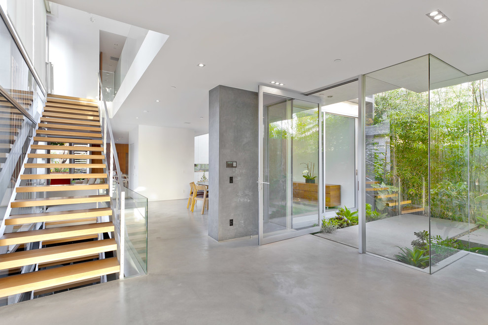 Photo of a large modern foyer in Los Angeles with concrete floors, a pivot front door and a glass front door.