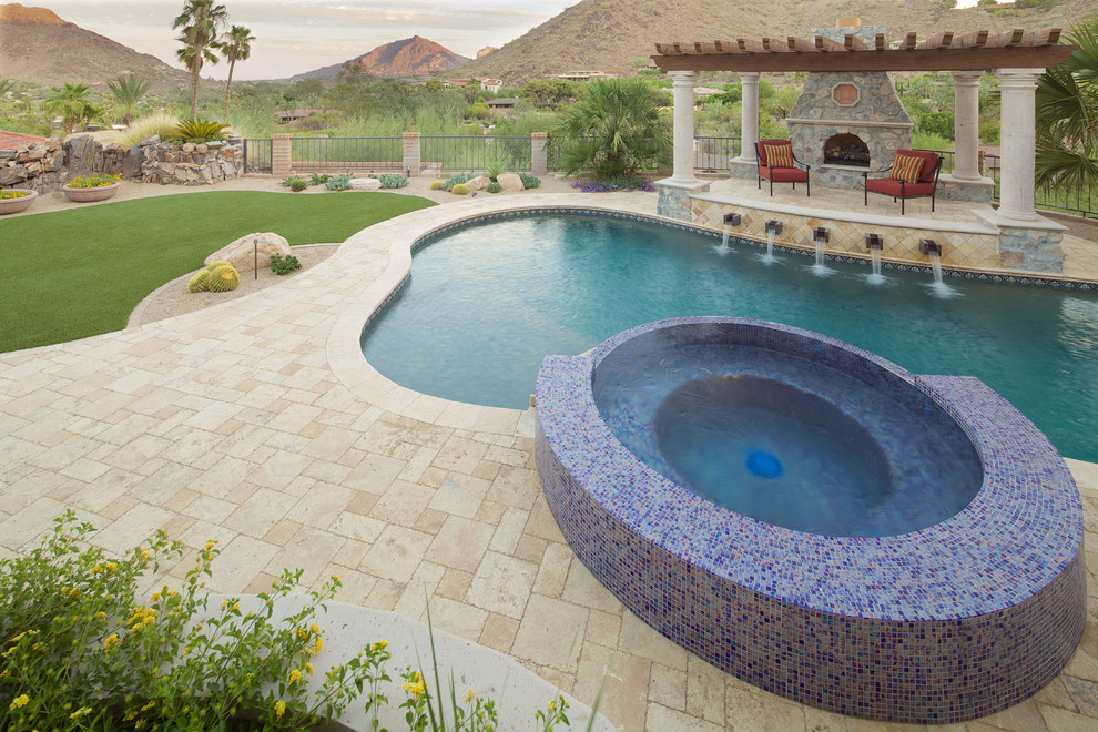 Photo of a large mediterranean backyard custom-shaped natural pool in Phoenix with a pool house and natural stone pavers.