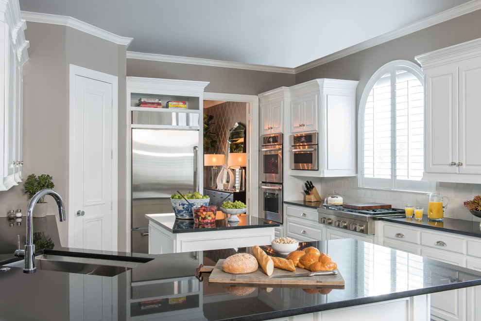 Open concept kitchen - mid-sized transitional u-shaped dark wood floor open concept kitchen idea in Dallas with an undermount sink, recessed-panel cabinets, white cabinets, granite countertops, white backsplash, stone tile backsplash, stainless steel appliances and an island