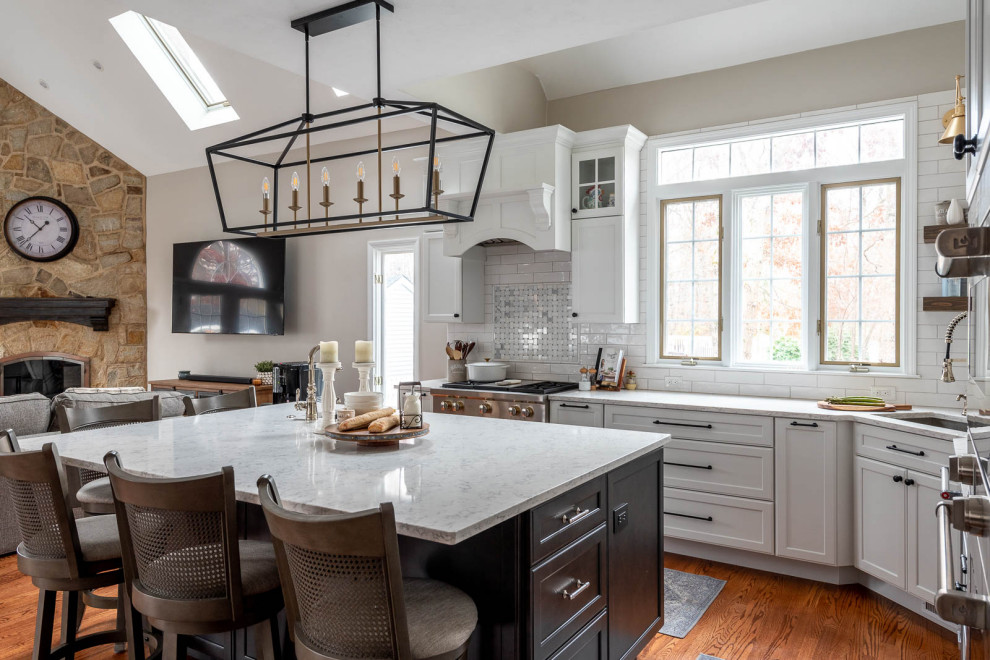 Inspiration for an expansive transitional l-shaped open plan kitchen in Boston with an undermount sink, shaker cabinets, white cabinets, quartz benchtops, white splashback, subway tile splashback, stainless steel appliances, dark hardwood floors, with island, brown floor, white benchtop and vaulted.