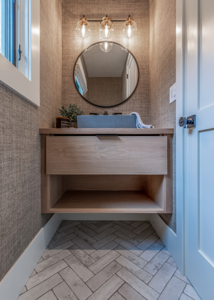 This is an example of a large beach style cloakroom in Denver with freestanding cabinets, light wood cabinets, beige walls, ceramic flooring, a vessel sink, wooden worktops, white floors, a floating vanity unit and wallpapered walls.