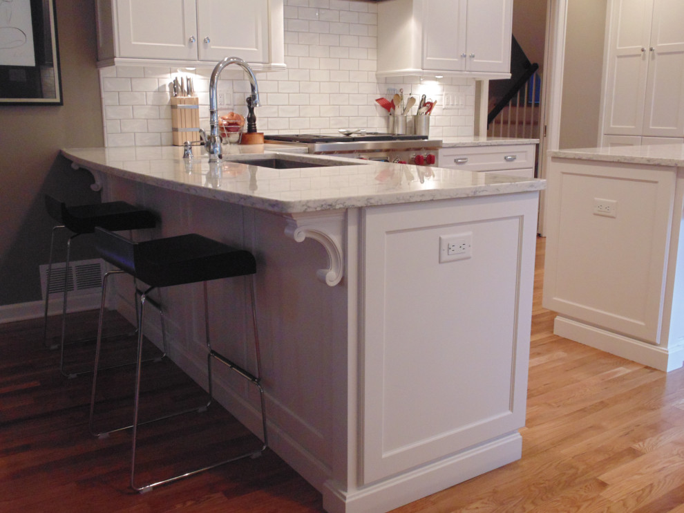 Large transitional u-shaped medium tone wood floor and brown floor eat-in kitchen photo with an undermount sink, recessed-panel cabinets, white cabinets, quartz countertops, white backsplash, subway tile backsplash, stainless steel appliances, an island and white countertops