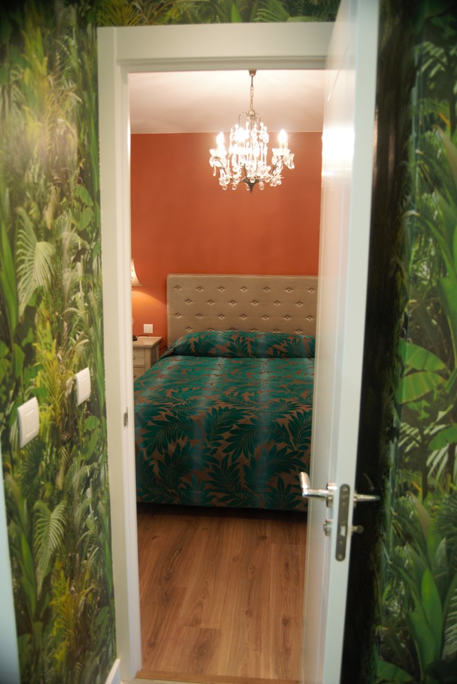 Diseño de habitación de invitados bohemia de tamaño medio con parades naranjas, suelo laminado y suelo marrón