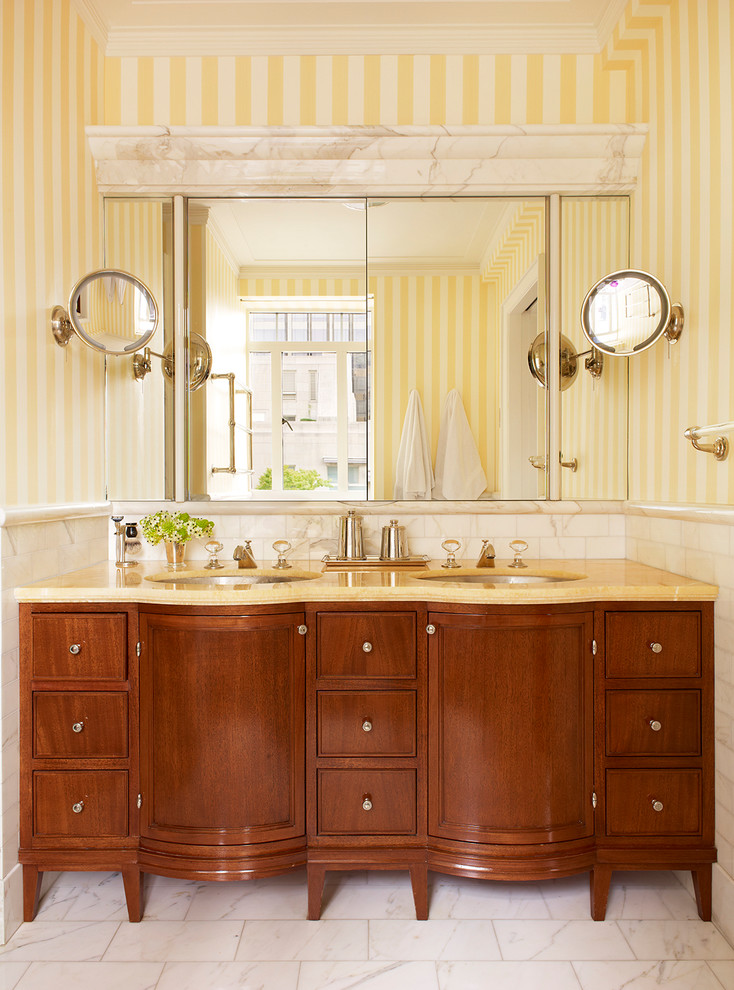 Inspiration for a mid-sized traditional master bathroom in New York with furniture-like cabinets, medium wood cabinets, white tile, stone tile, yellow walls, marble floors, an undermount sink and onyx benchtops.