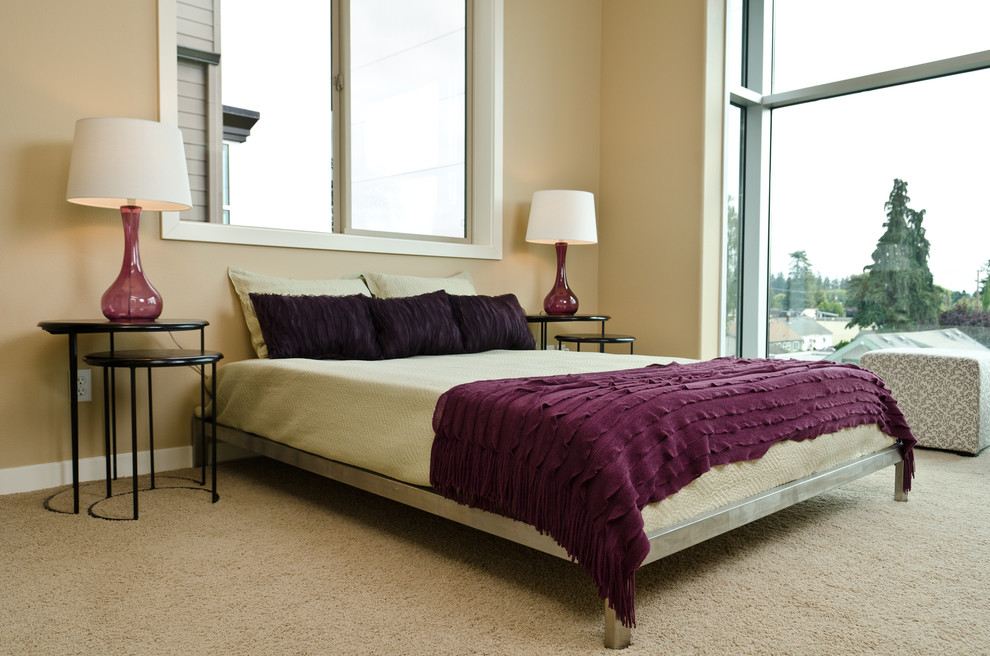 This is an example of a contemporary bedroom in Portland with beige walls and carpet.