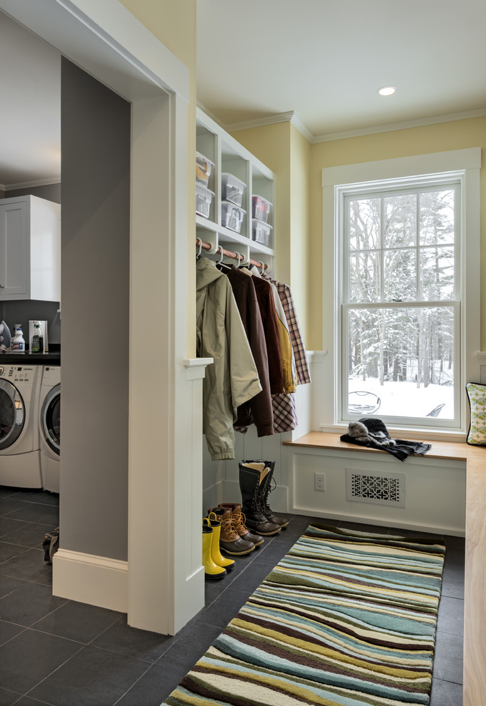 This is an example of a mid-sized traditional mudroom in Portland Maine with yellow walls and slate floors.