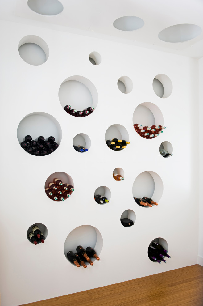 This is an example of an industrial wine cellar in Other with medium hardwood floors, storage racks and brown floor.