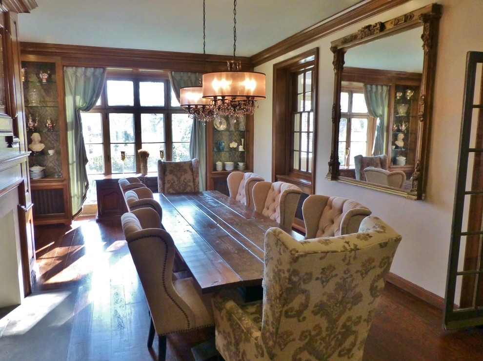 This is an example of a large traditional separate dining room in Philadelphia with white walls, dark hardwood floors, a standard fireplace, a wood fireplace surround and brown floor.