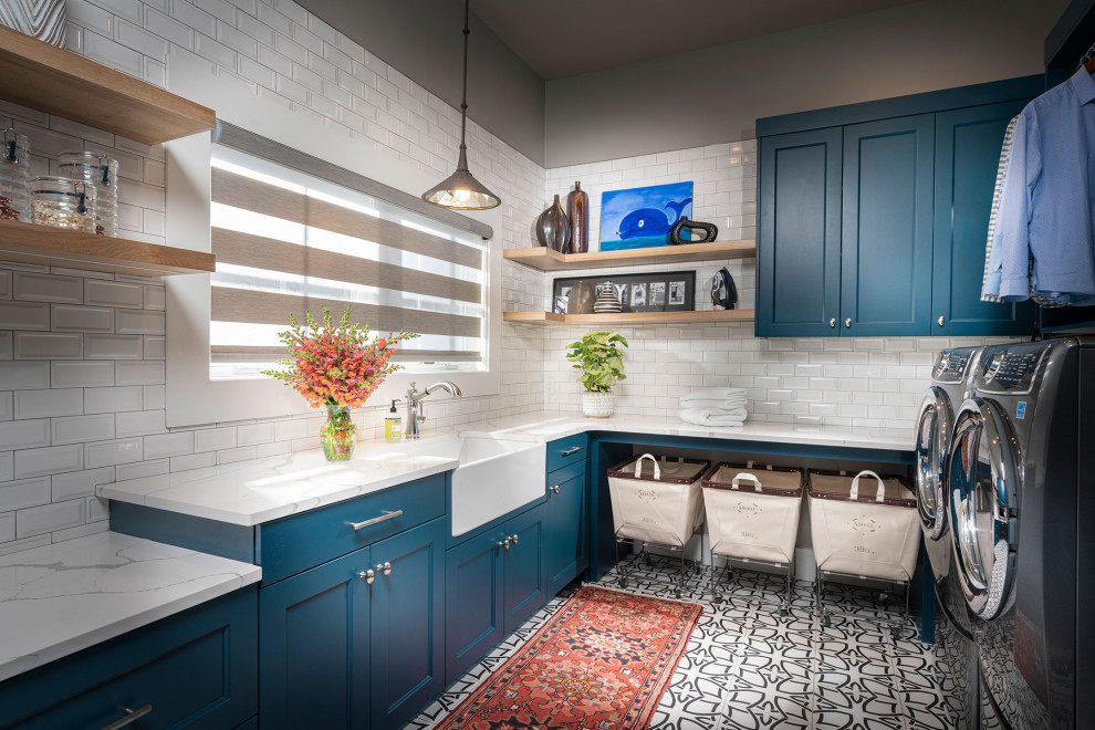 Photo of a large transitional u-shaped utility room in Other with an undermount sink, blue cabinets, quartz benchtops, ceramic floors, a side-by-side washer and dryer, white floor, white benchtop, recessed-panel cabinets and grey walls.
