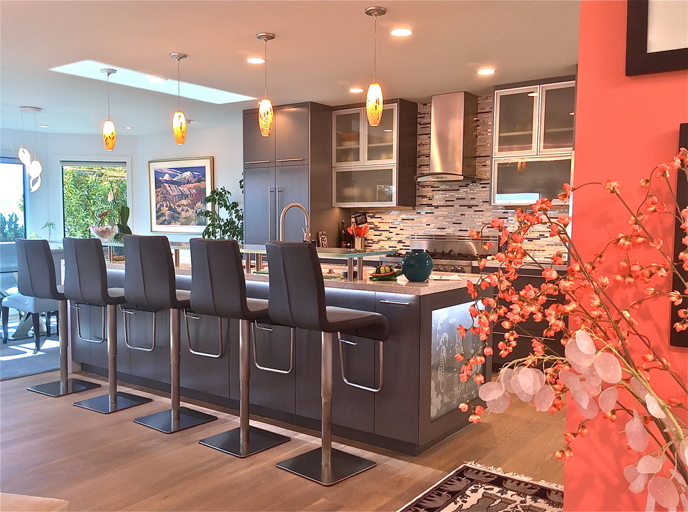 Photo of a mid-sized modern galley open plan kitchen in San Luis Obispo with an undermount sink, grey cabinets, multi-coloured splashback, stainless steel appliances, medium hardwood floors, with island, flat-panel cabinets, quartz benchtops, matchstick tile splashback and brown floor.