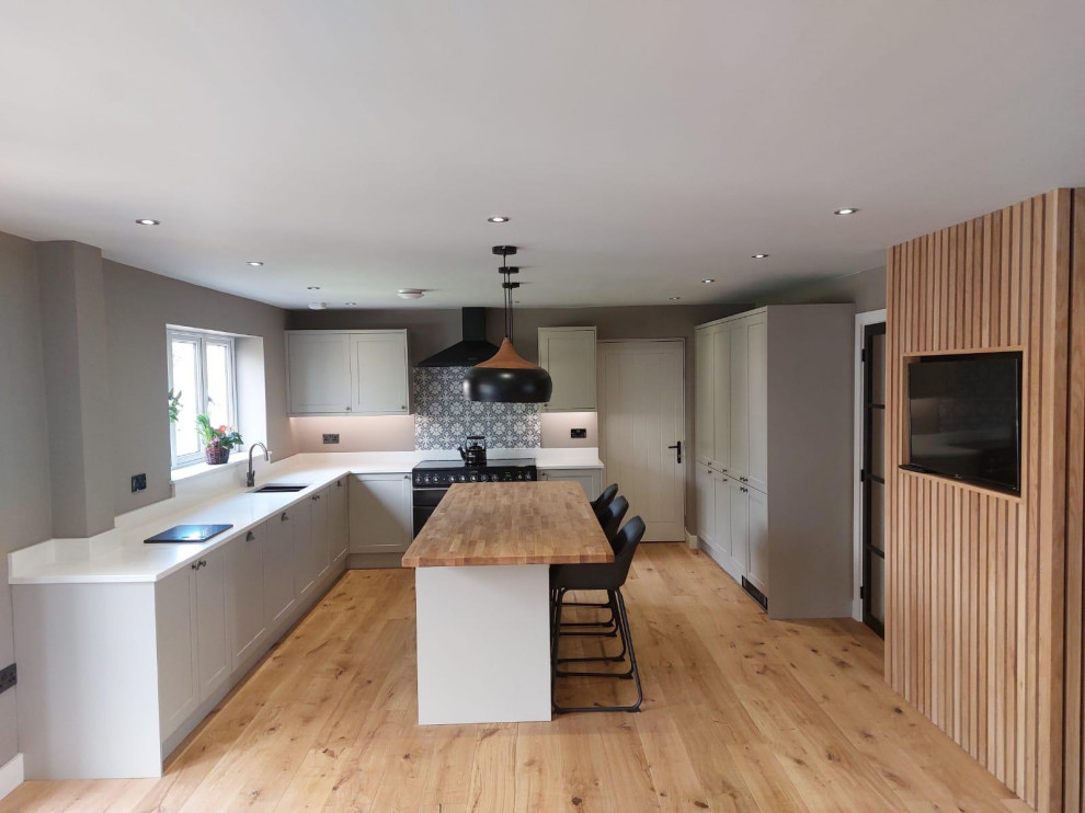 This is an example of a large contemporary kitchen/diner in Other with a built-in sink, shaker cabinets, multi-coloured splashback, cement tile splashback, black appliances, an island and a feature wall.