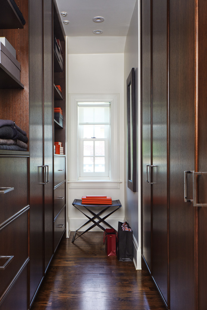 This is an example of a small transitional gender-neutral walk-in wardrobe in Toronto with dark wood cabinets and dark hardwood floors.