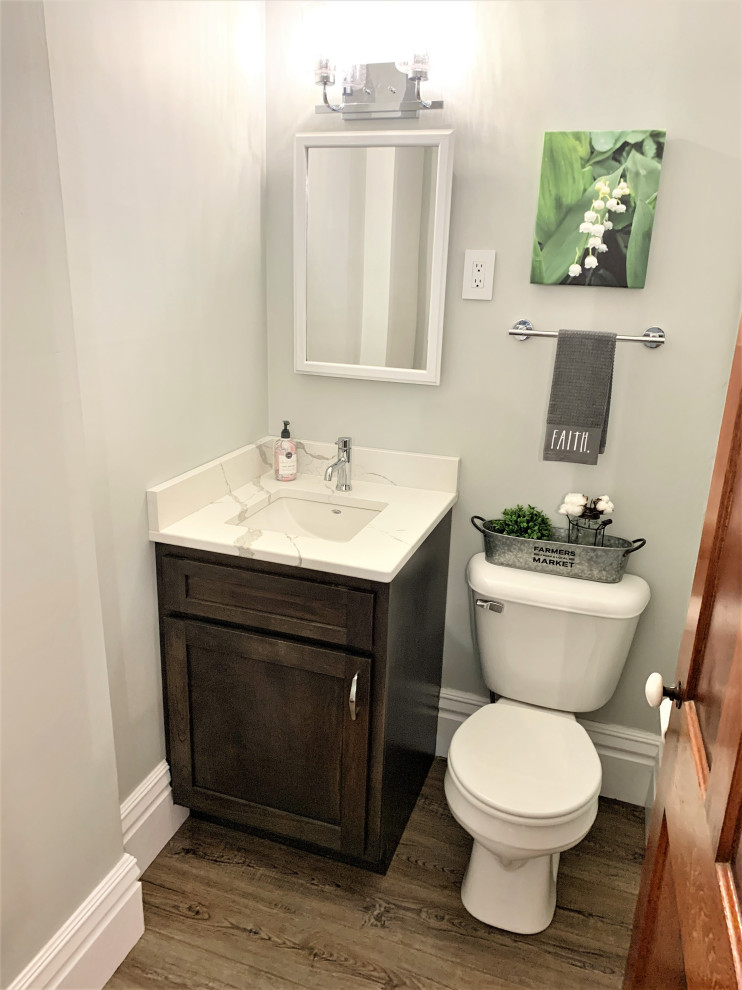 Cette image montre un WC et toilettes traditionnel de taille moyenne avec un placard à porte plane, des portes de placard blanches, un sol en vinyl et un sol marron.