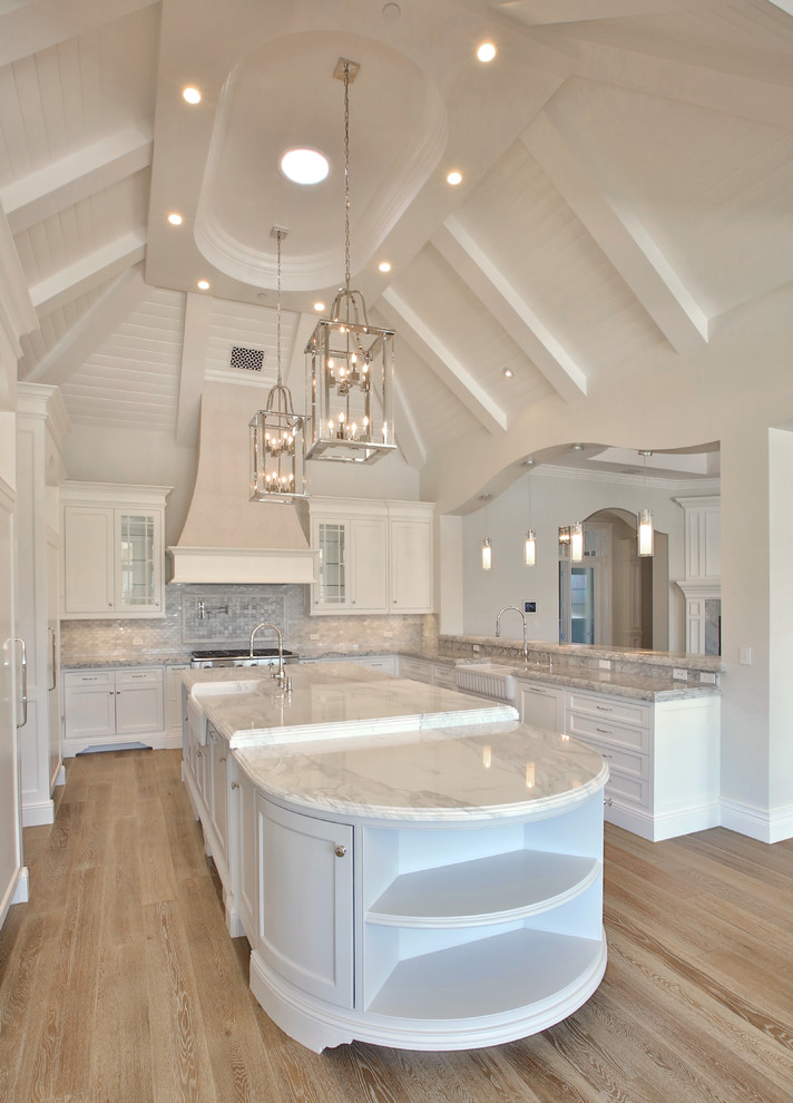 Open concept kitchen - huge transitional u-shaped light wood floor open concept kitchen idea in Phoenix with a farmhouse sink, shaker cabinets, white cabinets, marble countertops, gray backsplash, glass tile backsplash, stainless steel appliances and an island