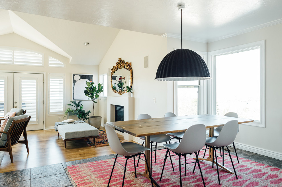 Design ideas for a mid-sized eclectic open plan dining in Salt Lake City with white walls, slate floors, a standard fireplace, a plaster fireplace surround and grey floor.
