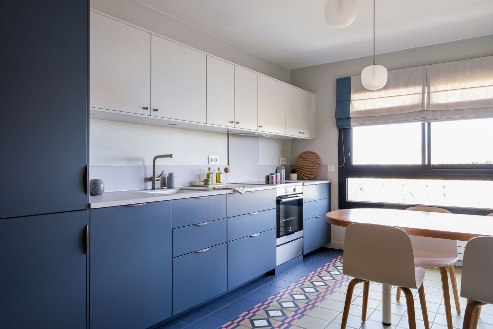 Cette image montre une cuisine linéaire design de taille moyenne avec un placard à porte plane, des portes de placard bleues, carreaux de ciment au sol, un sol multicolore, un plan de travail gris et machine à laver.