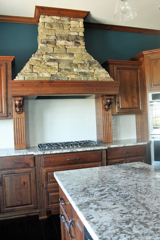 Mountain style u-shaped dark wood floor eat-in kitchen photo with granite countertops, white backsplash, subway tile backsplash, stainless steel appliances, an island, raised-panel cabinets and dark wood cabinets
