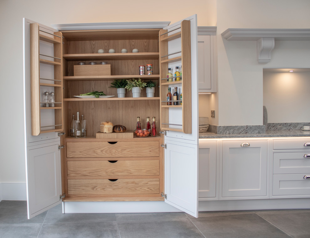 This is an example of a large traditional single-wall eat-in kitchen in Devon with an integrated sink, white cabinets, granite benchtops, grey splashback, black appliances, slate floors, with island, grey floor and grey benchtop.