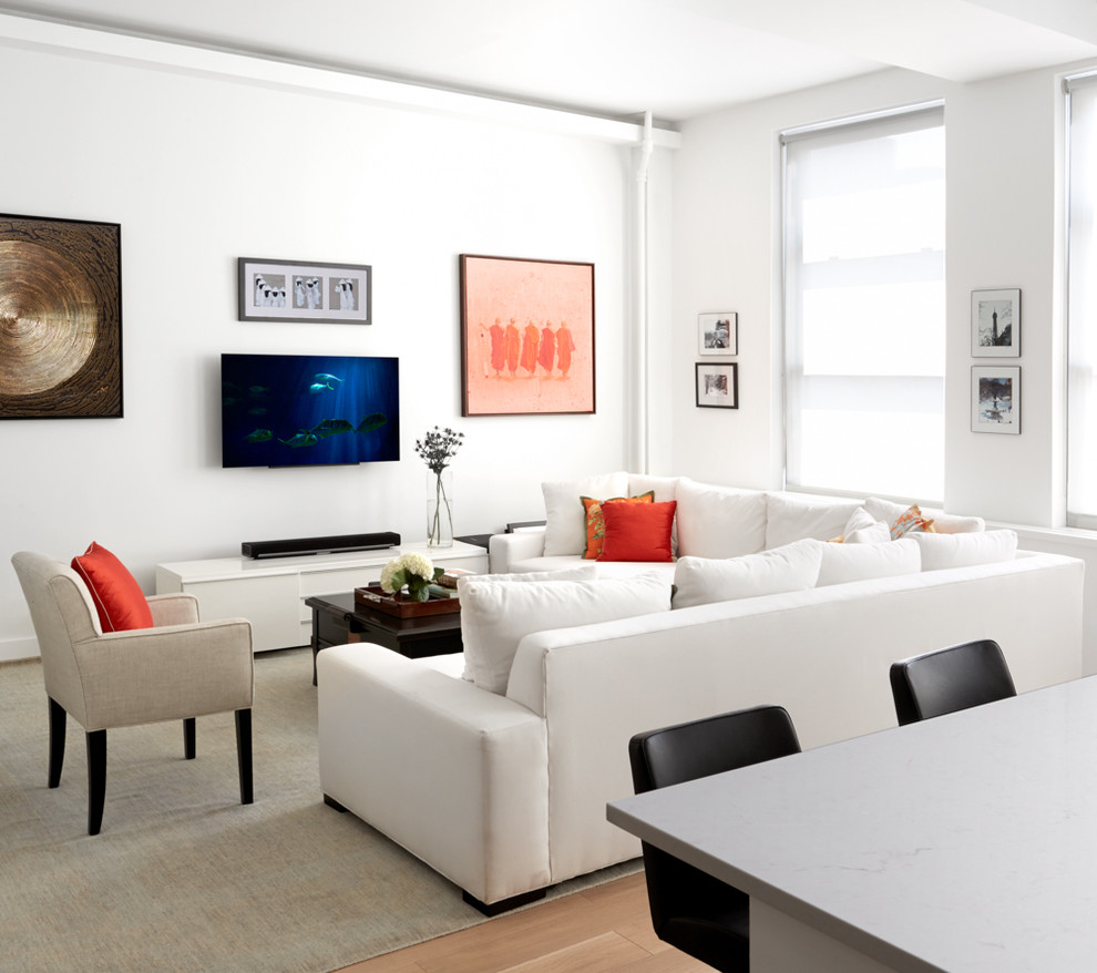 This is an example of a mid-sized contemporary formal open concept living room in New York with white walls, light hardwood floors, a wall-mounted tv and beige floor.