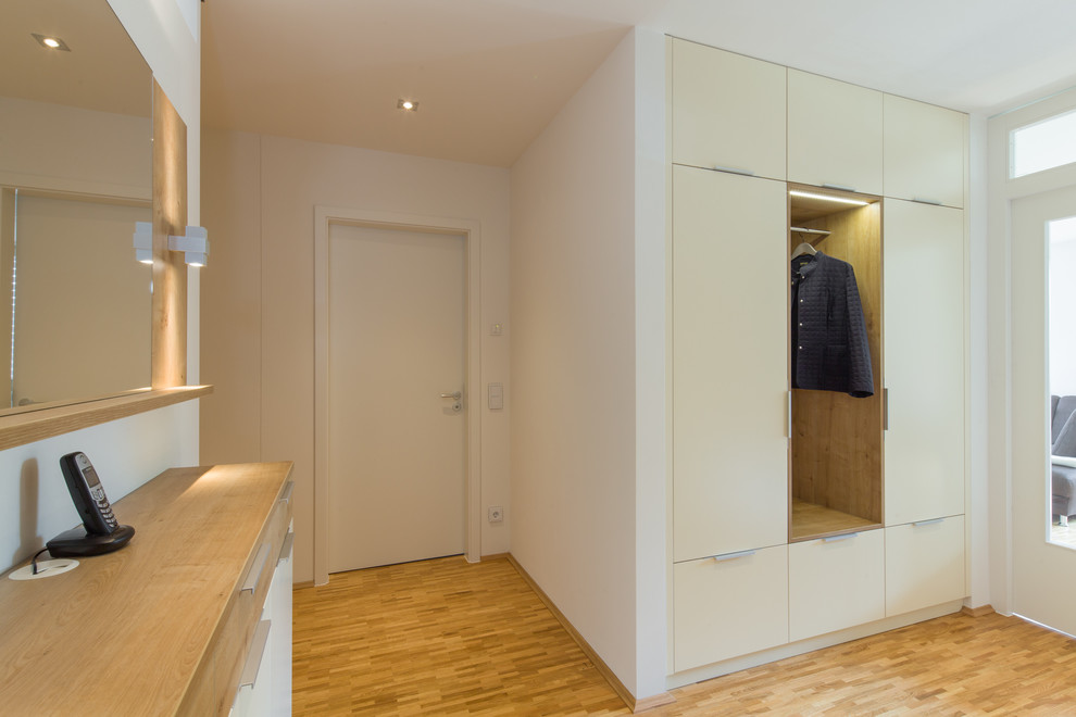 This is an example of a mid-sized contemporary hallway in Dresden with white walls and medium hardwood floors.