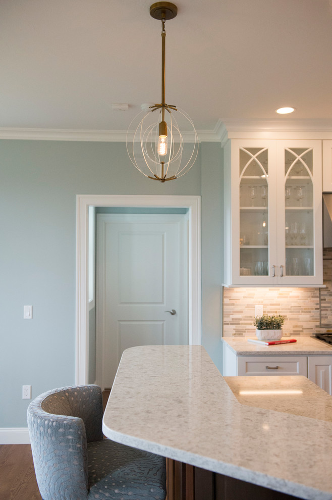 Inspiration for a transitional l-shaped medium tone wood floor home design remodel in Boston with white cabinets, granite countertops, gray backsplash, stainless steel appliances and an island