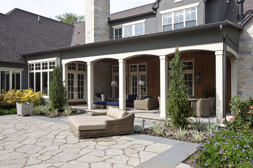 Design ideas for a mid-sized traditional backyard patio in Milwaukee with natural stone pavers and a roof extension.
