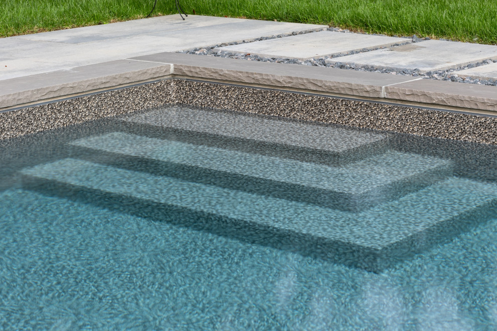 Ejemplo de piscina clásica renovada grande rectangular en patio trasero con paisajismo de piscina y adoquines de hormigón